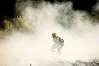 A firefighters battling the Windy Fire extinguishes a spot fire near the Trail of 100 Giants grove of Sequoia National Forest, Calif., on Sunday, Sept. 19, 2021. (AP Photo/Noah Berger)