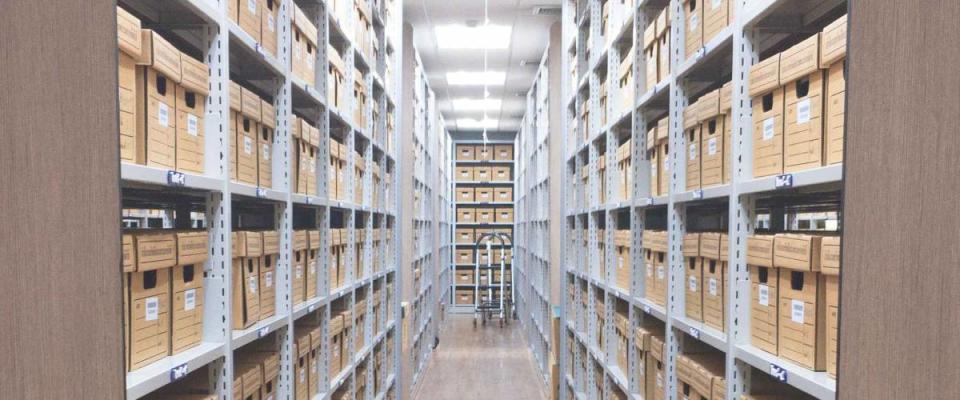 Brown filing boxes stacked on rows of shelves in a warehouse