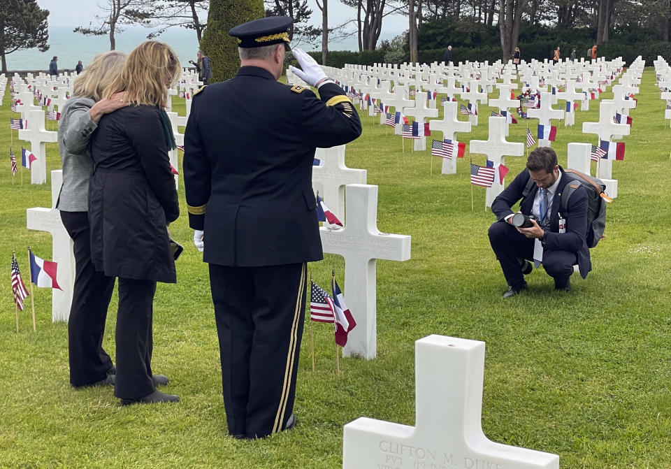 Associated Press reporter Tara Copp, second from left, stands with Joint Chiefs Chairman Gen. Mark Milley, third from left, and his wife Hollyanne, as they pause at the Normandy American Cemetery gravesite of Pfc. Terry Harris, Copp's great-uncle, in Colleville-sur-Mer, Normandy, France, June 6, 2023. Copp was covering Milley's last trip to Normandy as a U.S. soldier. Milley served in both airborne divisions who jumped into Normandy on June 6, 1944, and commanded the 506th Parachute Infantry Regiment, which was Harris' unit. (Oren Lieberman/CNN via AP)