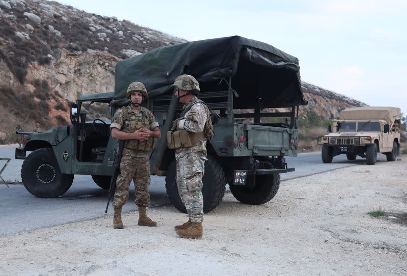 Members of the Lebanese army stand near military vehicles in Kfar Kila village as pictured from Khiam, near the border with Israel