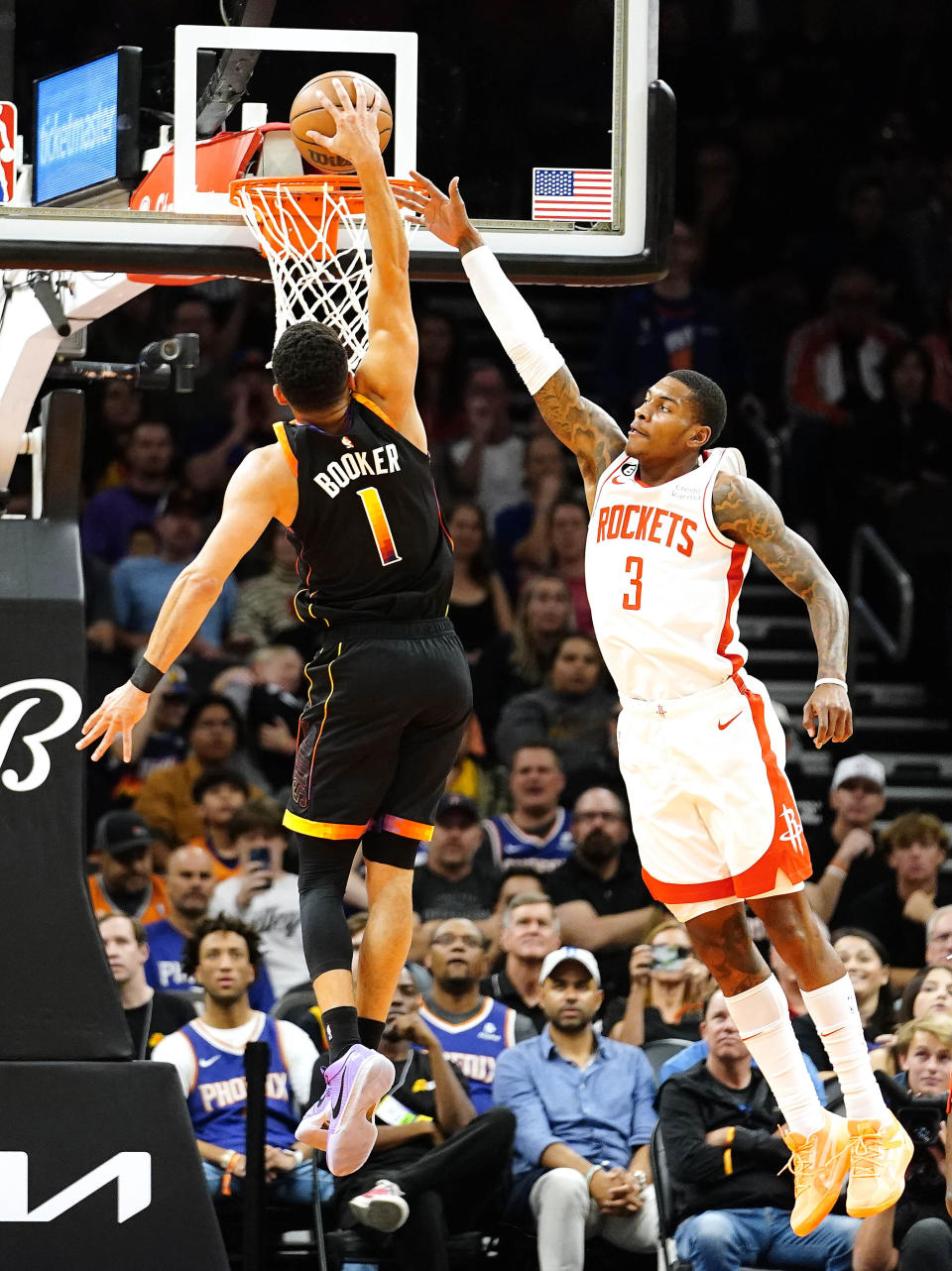 Phoenix Suns' Devin Booker (1) dunks past Houston Rockets' Kevin Porter Jr. (3) during the first half of an NBA basketball game, Sunday, Oct. 30, 2022, in Phoenix. (AP Photo/Darryl Webb)