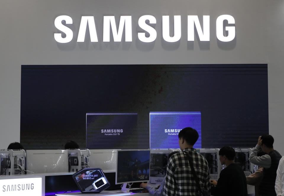 Visitors tour near the logo of Samsung Electronics at semiconductor exhibition in Seoul, South Korea, Tuesday, Oct. 8, 2019. Samsung Electronics has predicted its operating profit for the last quarter will fall by more than 56% from a year earlier amid sluggish global demand for computer chips. (AP Photo/Lee Jin-man)