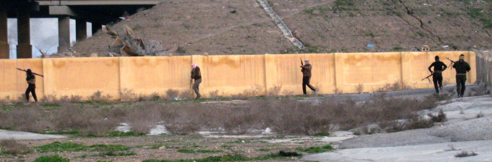 Gunmen run for cover during clashes with Iraqi security forces outside Fallujah, 40 miles (65 kilometers) west of Baghdad, Iraq, Sunday, Jan. 19, 2014. Violence across Iraq, including a series of car bombings and fighting between militants and government troops over control of the country's contested Anbar province, killed dozens Saturday, officials said. (AP Photo)