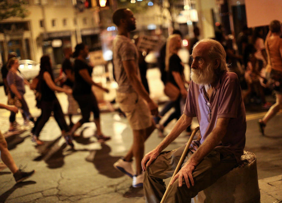 <p>A man watches demonstrators march during a protest in Atlanta on Friday, Sept. 23, 2016 in response to the police shooting deaths of Terence Crutch in Tulsa, Okla. and Keith Lamont Scott in Charlotte, N.C. (AP Photo/Branden Camp)</p>