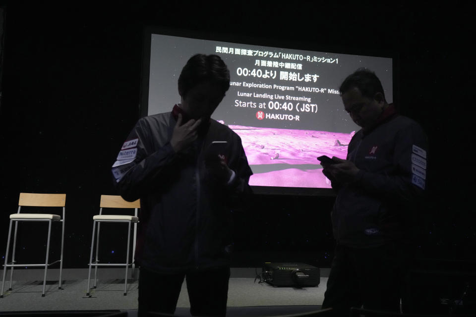 Staff stand in front of the screen prior to livestream of the lunar landing event Wednesday, April 26, 2023, at Miraikan, the National Museum of Emerging Science and Innovation, in Tokyo. Tokyo's ispace company put its own spacecraft into orbit around the moon a month ago. Flight controllers will direct the craft, named Hakuto, Japanese for white rabbit, to descend from 60 miles (100 kilometers) high and land on Wednesday. (AP Photo/Eugene Hoshiko)