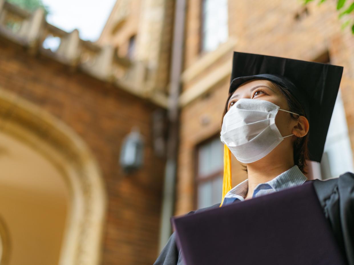 A low angle portrait of a student in graduate gown with a diploma.