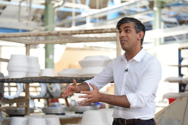 Rishi Sunak in a white shirt, gesturing to someone off camera with his hands