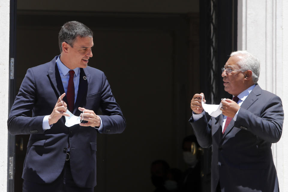 Spain's Prime Minister Pedro Sanchez, left, and Portugal's Prime Minister Antonio Costa take off their masks to pose for pictures as they meet at the Sao Bento palace in Lisbon, Monday, July 6, 2020. (AP Photo/Armando Franca)