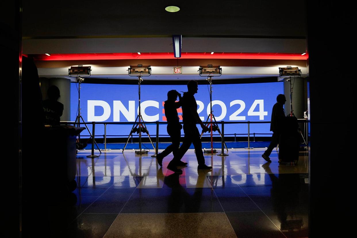 Workers walk past signage during preparations before the start of the Democratic National Convention at the United Center on Aug 18, 2024.