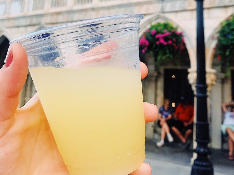 hand holding a yellow cocktail in epcot at disney world