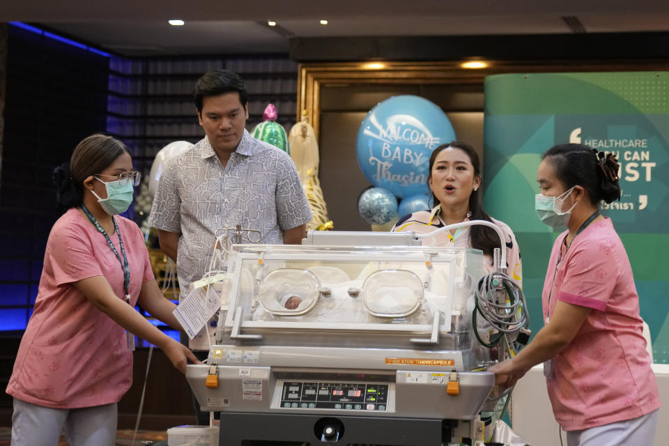 Paetongtarn Shinawatra, center, a leading Thai politician and youngest daughter of exiled former deposed Thai leader Thaksin Shinawatra, second right, stands behind an incubator with her new born son, along with, second on left her husband Pidok Sooksawas during press conference in Bangkok, Thailand, Wednesday, May 3, 2023. Paetongtarn is running for the Pheu Thai party, which is heavily favored to win the most seats in the May 14 general election, and is one of their candidates to become the next prime minister. (AP Photo/Sakchai Lalit)