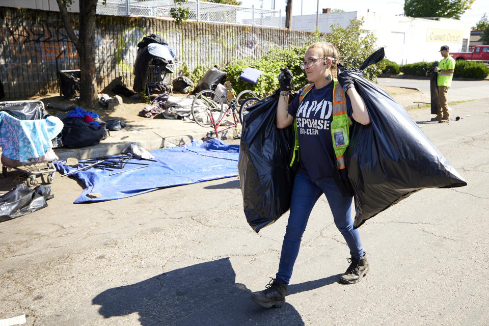 THIS CORRECTS THE NAME OF THE CONTRACTOR TO RAPID RESPONSE BIO CLEAN, NOT RAPID RESPONSE BIO CLEANUP AS ORIGINALLY SENT - Amber Nastasia from Rapid Response Bio Clean cleans a homeless camp in Portland, Ore., Thursday, July 27, 2023. Cities across the U.S. are struggling with and cracking down on tent encampments as the number of homeless people grows, largely due to a lack of affordable housing. Homeless people and their advocates say sweeps are cruel and costly, and there aren't enough homes or beds for everyone. (AP Photo/Craig Mitchelldyer)