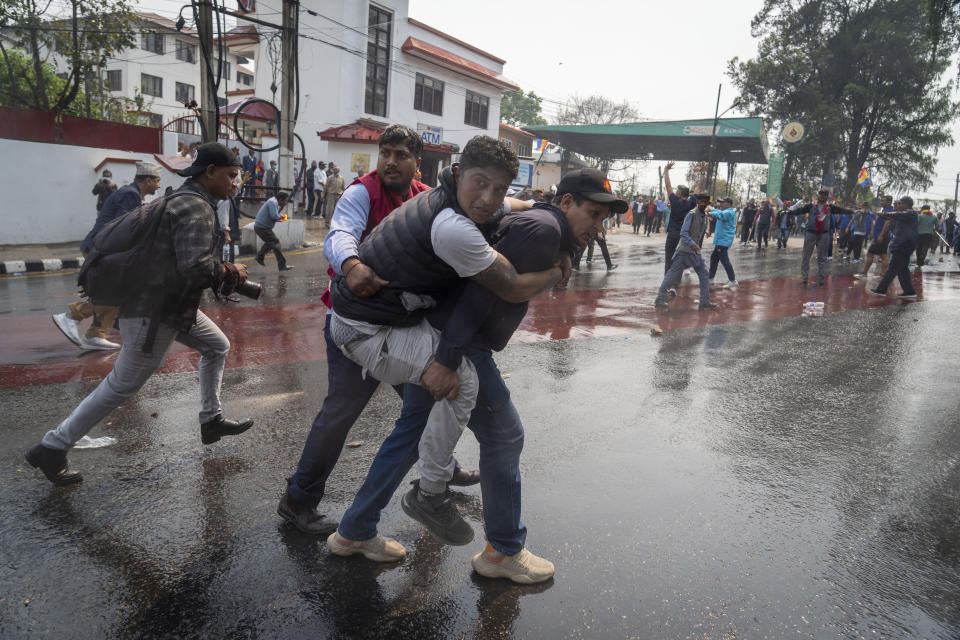 An injured supporter of Rastriya Prajatantra Party, or national democratic party is helped by his friends after clash with policemen as they take part in a protest demanding a restoration of Nepal's monarchy in Kathmandu, Nepal, Tuesday, April 9, 2024. Riot police used batons and tear gas to halt hundreds of supporters of Nepal's former king demanding the restoration of the monarchy and the nation's former status as a Hindu state. Weeks of street protests in 2006 forced then King Gyanendra to abandon his authoritarian rule and introduce democracy. (AP Photo/Niranjan Shrestha)