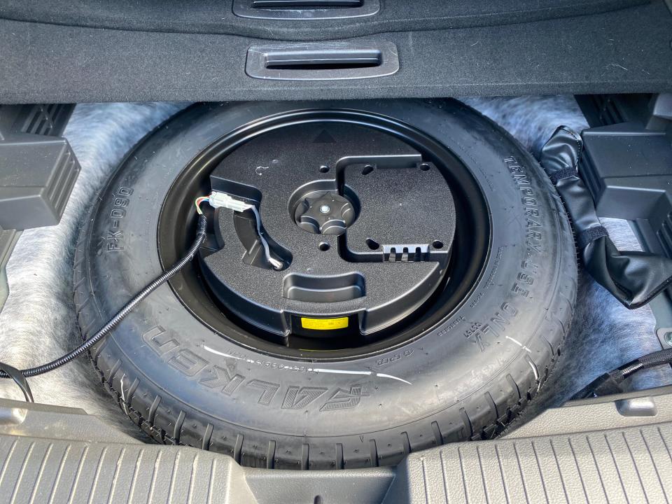 The spare tire and stereo subwoofer underneath the rear cargo area of a 2024 Nissan Rogue SL SUV.