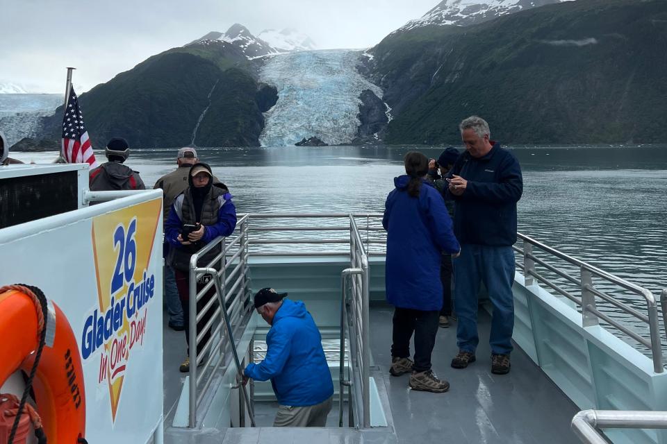 group of people on deck of boat in front of glaciers