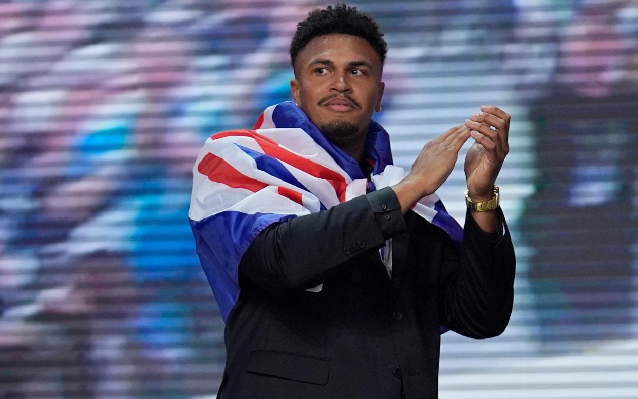 Travis Clayton takes to the stage at the NFL Draft with a Union Flag around his shoulders