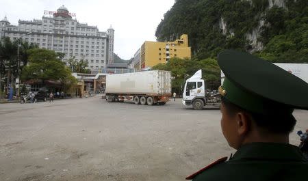 A border guard (R) monitors people and container trucks crossing the Tan Thanh border gate with China in Vietnam's northern Lang Son province in this July 30, 2014 file photo. REUTERS/Kham/Files