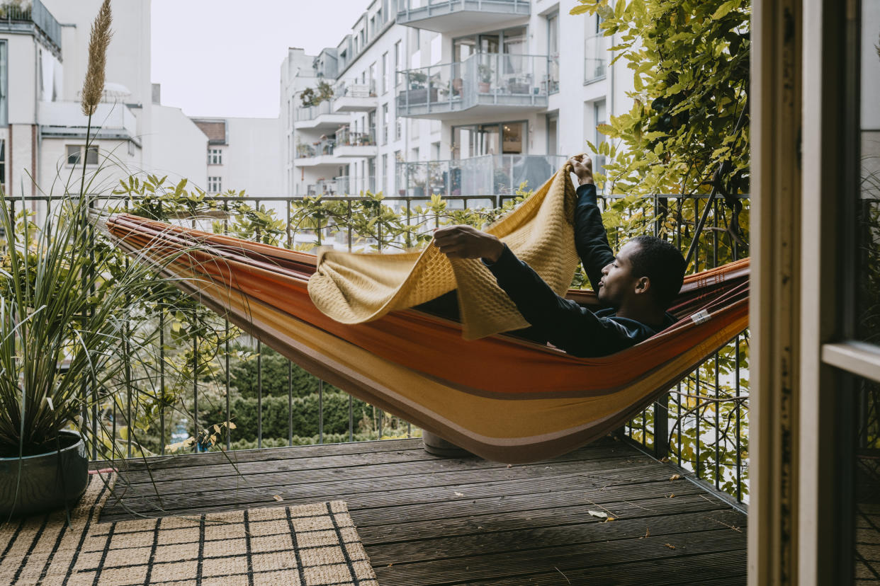 man laying in hammock outside on patio during summer with blanket
