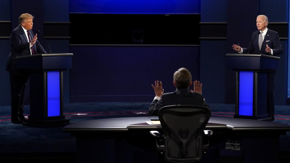 Two men stand at podiums with a moderator seated between them.