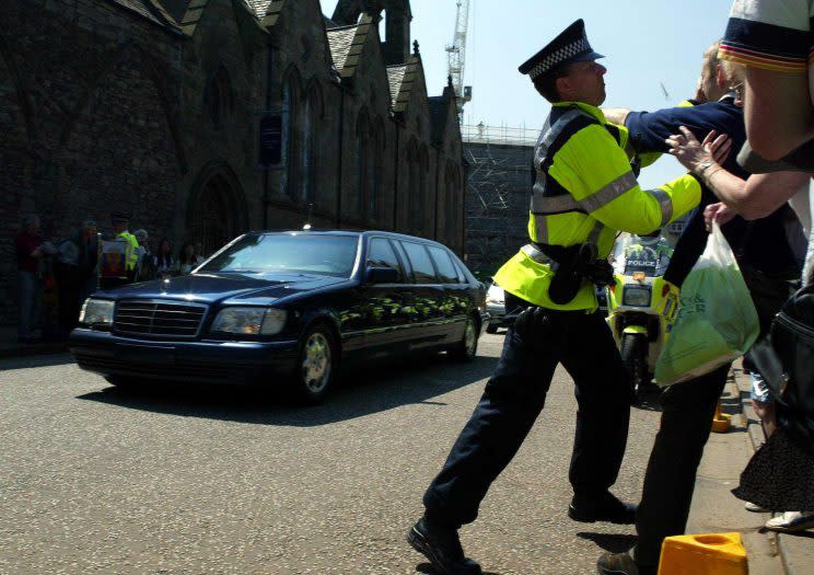 A protester against the war in Chechyna is arrested by police officers as President Putin's entourage passed through the gates of the Palace of Holyroodhouse (PA)