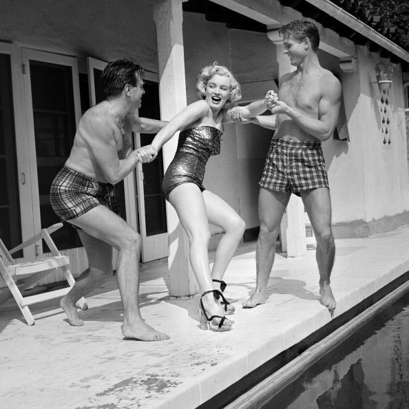 <p>Marilyn Monroe resists being thrown into the water by two male friends during a pool day in 1950. </p>