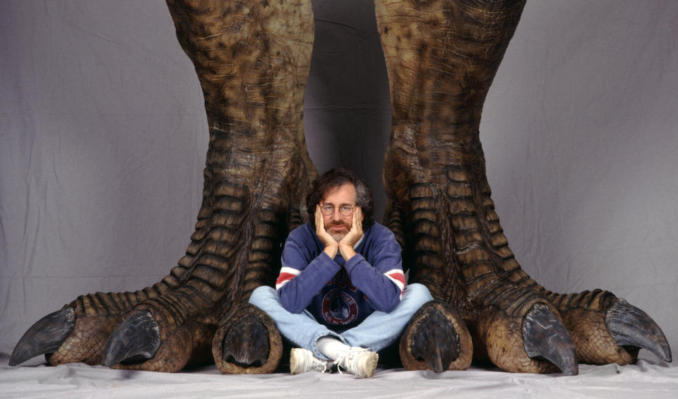 American director Steven Spielberg poses between a pair of giant dinosaur feet in a publicity still for the film 'Jurassic Park', 1993.  (Photo by Murray Close/Getty Images)