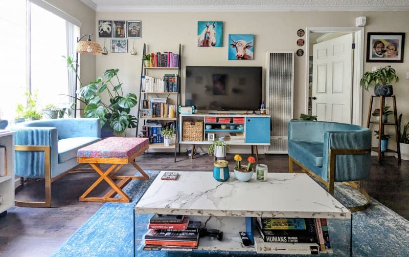 beige/off white living room with blue rug and matching curved blue velvet chairs