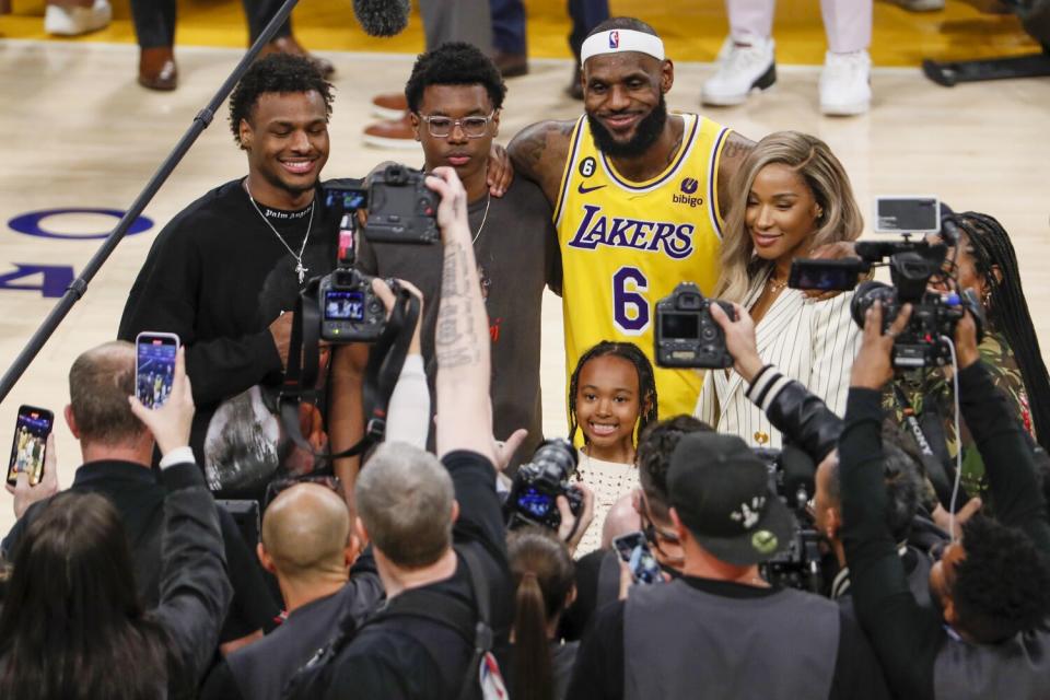 Bronny James, left, joins brother Bryce and mother Savannah for a photo after his father LeBron set the NBA scoring record.