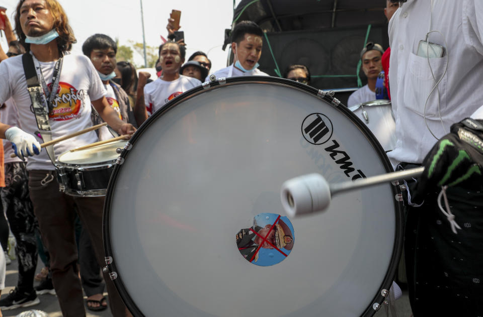An anti-coup protester beats a drum with a defaced image of Commander-in-Chief Senior Gen. Min Aung Hlaing during a street march in Mandalay, Myanmar, Thursday, Feb. 25, 2021. Social media giant Facebook announced Thursday it was banning all accounts linked to Myanmar's military as well as ads from military-controlled companies in the wake of the army's seizure of power on Feb. 1. (AP Photo)