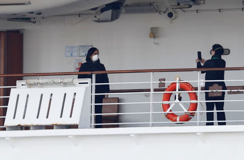 Passengers take photos on a deck of the cruise ship Diamond Princess at Daikoku Pier Cruise Terminal in Yokohama, south of Tokyo, Japan