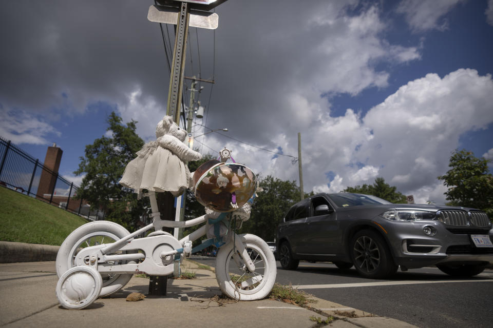 A vehicle drives past a memorial for 5-year-old Allie Hart, who was struck and killed in 2021 by a driver while riding her bicycle in a crosswalk, Monday, Sept. 11, 2023, in Washington. (AP Photo/Mark Schiefelbein)