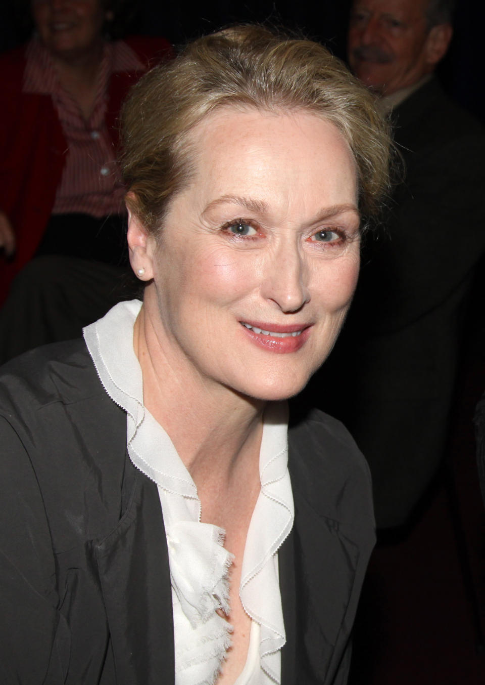 Close-up of Meryl smiling in a frilly blouse and jacket