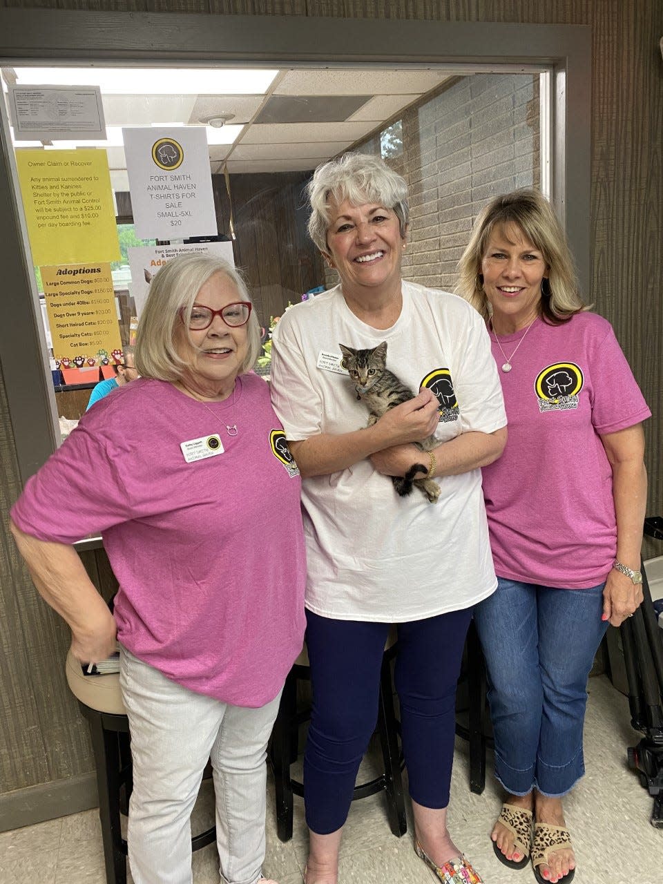 Brenda Altman holds Cash , the infamous kitten who got stuck in an ATM. Kathy Ligget  stands at her left, and Laura Blythe stands at her right.