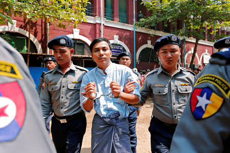 Detained Reuters journalist Kyaw Soe Oo is escorted by police after a court hearing in Yangon, Myanmar. REUTERS/Stringer