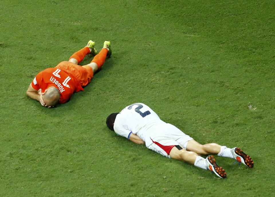 Arjen Robben of the Netherlands and Costa Rica's Johnny Acosta lie on the pitch after colliding with each other during extra time in their 2014 World Cup quarter-finals at the Fonte Nova arena in Salvador July 5, 2014. Acosta was shown yellow card for the action. REUTERS/Ruben Sprich (BRAZIL - Tags: SOCCER SPORT WORLD CUP)