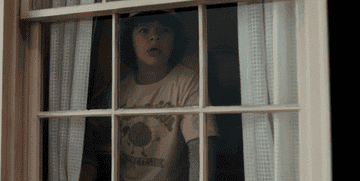 Gaten Matarazzo hurriedly shuts the curtains as his character, Dustin, from "Stranger Things"