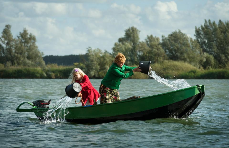 Women bailing water out of boat in lake.