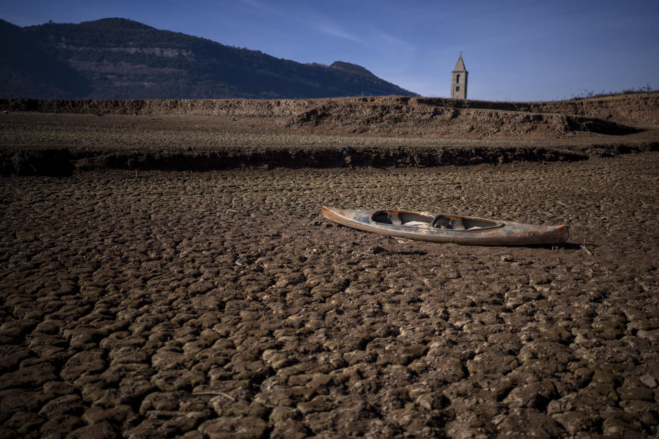 An abandoned canoe lies on the cracked ground at the Sau reservoir, which is only at 5 percent of its capacity, in Vilanova de Sau, about 100 km (62 miles) north of Barcelona, Spain, Monday, Jan. 22, 2024. Barcelona and the surrounding area of Spain's northeast Catalonia are preparing to face tighter water restrictions amid a historic drought that has shrunk reservoirs to record lows. Catalonia has recorded below-average rainfall for 40 consecutive months. Experts say that the drought is driven by climate change and that the entire Mediterranean region is forecast to heat up at a faster rate than many other regions in the coming years. (AP Photo/Emilio Morenatti)