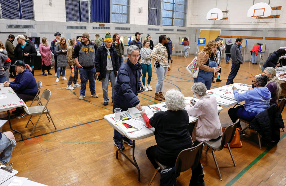 Voters line up to check in before casting their ballots inside a school gym. 