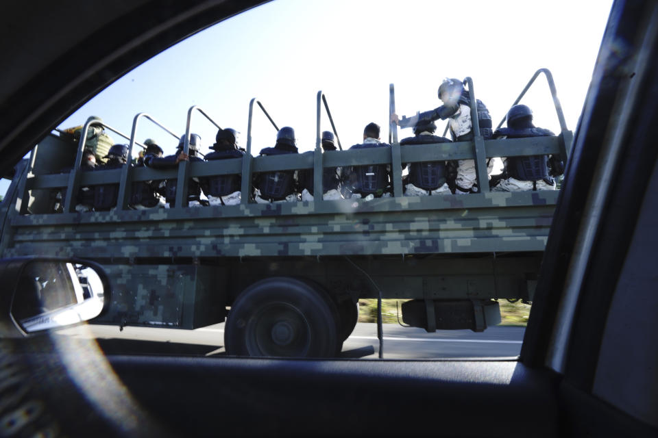 National Guards travel along the highway where migrants, mostly from Central America, head north by foot, along a coastal highway on the outskirts of Huixtla, Chiapas state, Mexico, Monday, Oct.25, 2021. The migrants had been waiting in Tapachula on Mexico's southern border for refugee or asylum papers that might allow them to travel, but grew tired of delays in the process, and left. (AP Photo/Marco Ugarte)