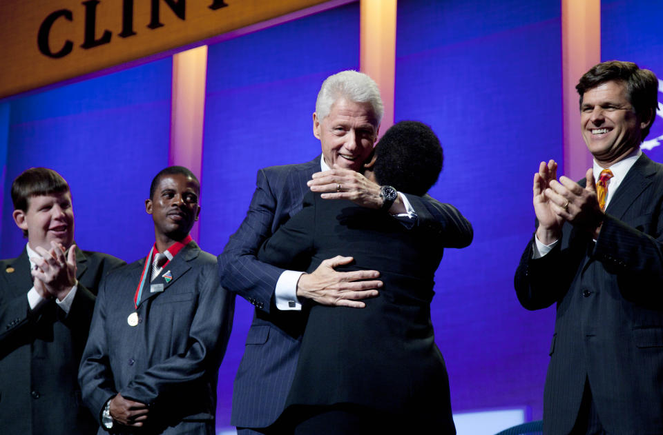 Former U.S. President Bill Clinton hugs Special Olympics athlete Loretta Claiborne after she addressed the opening session of the Clinton Global Initiative, Sunday, Sept. 23, 2012, in New York. From left are athletes Dustin Plunkett and Deon Namiseb. Tim Shriver, CEO of the Special Olympics, is at right. (AP Photo/Mark Lennihan)