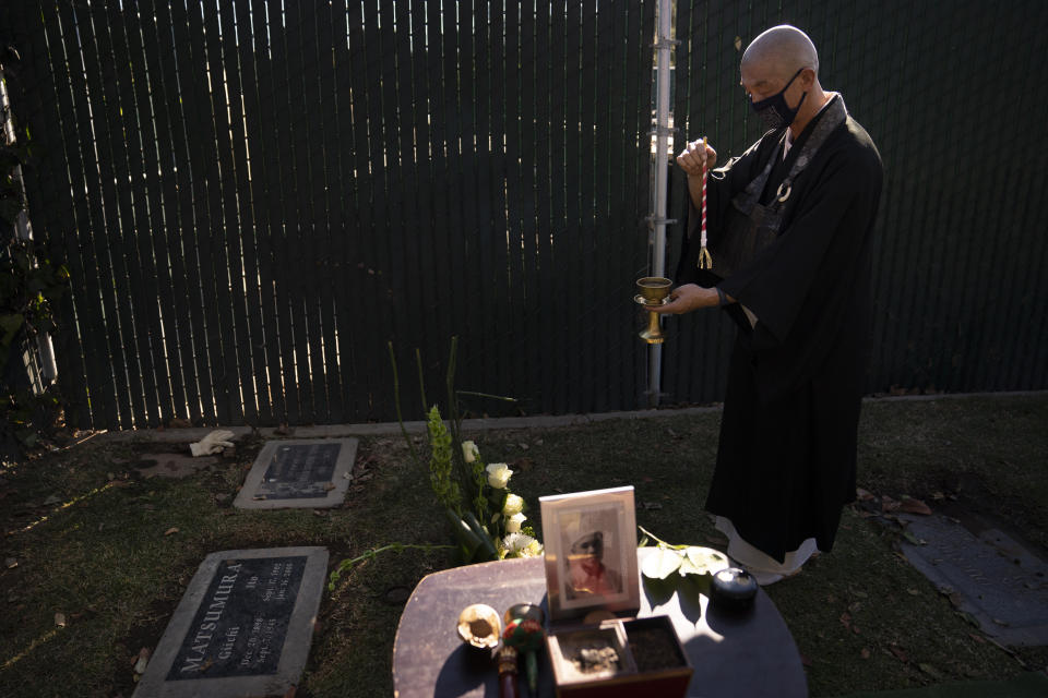 Shumyo Kojima, a head priest of Zenshuji Buddhist Temple, sprinkles purifying water over the grave of Giichi Matsumura during a memorial service at Woodlawn Cemetery in Santa Monica, Calif., Monday, Dec. 21, 2020. Giichi Matsumura, who died in the Sierra Nevada on a fishing trip while he was at the Japanese internment camp at Manzanar, was reburied in the same plot with his wife 75 years later after his remains were unearthed from a mountainside grave. (AP Photo/Jae C. Hong)