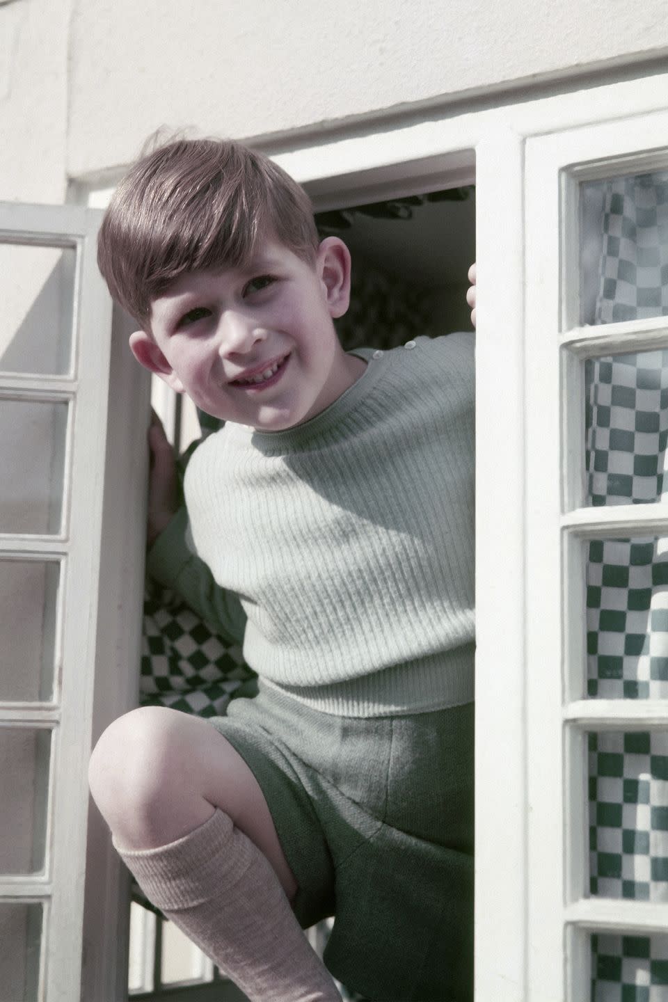 <p>Prince Charles smiles cheekily as he peeks out the window of a cottage in Windsor.</p>