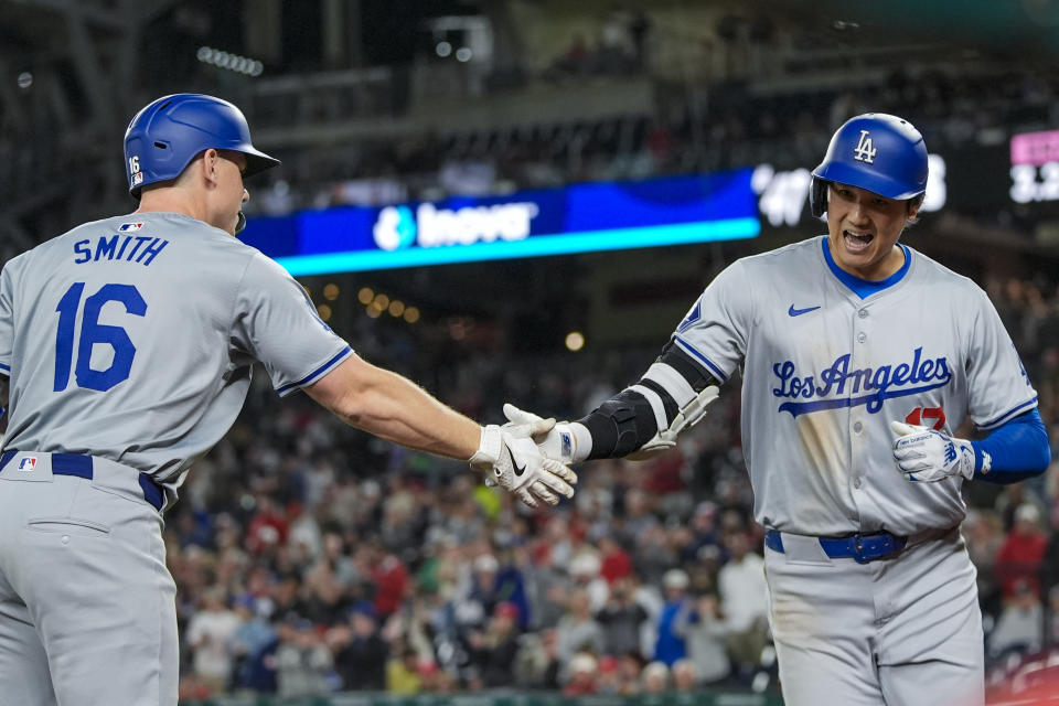 Los Angeles Dodgers designated hitter Shohei Ohtani, right, celebrates his solo home run with Will Smith during the ninth inning of a baseball game against the Washington Nationals at Nationals Park, Tuesday, April 23, 2024, in Washington. The Dodgers won 4-1. (AP Photo/Alex Brandon)