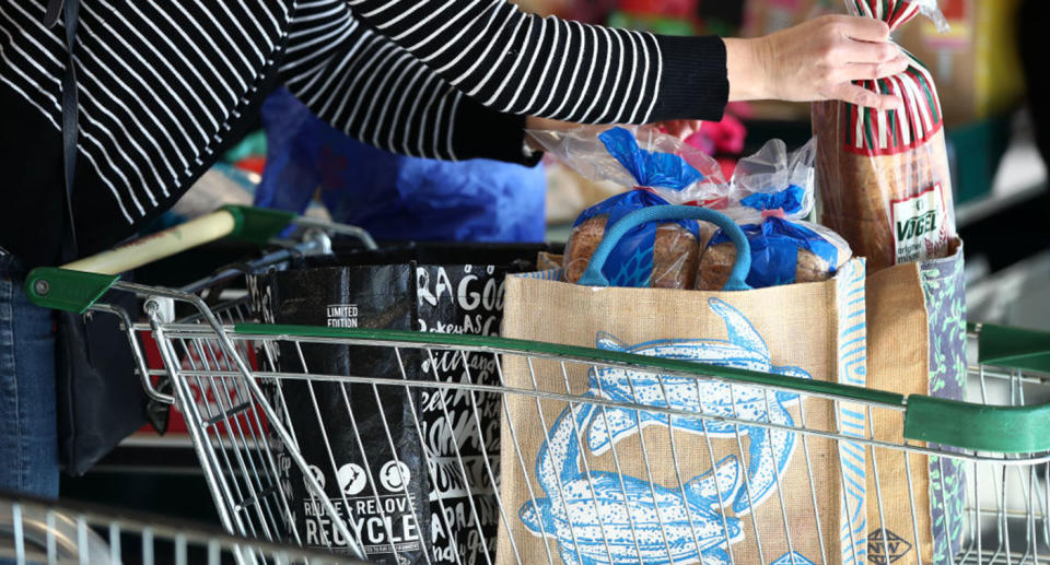 A woman puts items into a supermarket trolley.