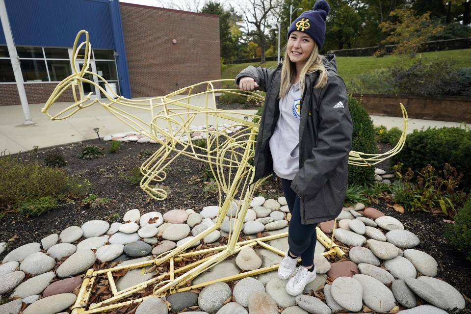 Madison Zurmuehlen stands next to a sculpture of the University of Missouri-Kansas City's mascot outside the soccer facility in Kansas City, Mo., Friday, Oct. 23, 2020. Amid pandemic restrictions aimed at keeping students safe and healthy, colleges are scrambling to help them adjust. Zurmuehlen said daily practices, with masks, are “the one thing I look forward to,” so it was tough when campus sports were canceled for two weeks after an outbreak among student athletes and staff. (AP Photo/Orlin Wagner)