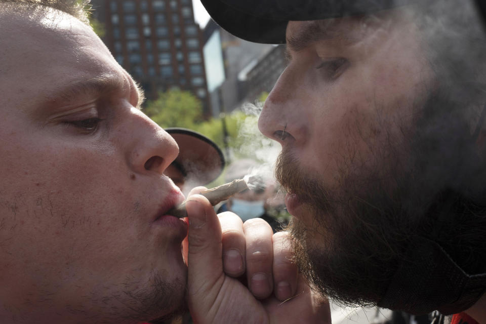 FILE — Michael Keren, left, and Scott Kisch smoke a marijuana cigarette during a "Joints for Jabs" event, April 20, 2021, in New York. New York began accepting applications, Thursday, Aug. 25, 2022, to open its first crop of legal recreational pot shops, taking a novel approach by reserving the first licenses for people with past pot convictions or their relatives. (AP Photo/Mark Lennihan, File)