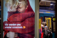 A pupil waits for a subway train in Frankfurt, Germany, Wednesday, Nov. 25, 2020. The German government will discuss further restrictions to avoid the outspread of the coronavirus. Letters on a an advertise read "we will embrace again". (AP Photo/Michael Probst)