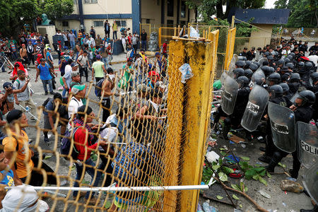 Men, part of a caravan of thousands of migrants from Central America en route to the U.S., push the border gate as they try to cross into Mexico and carry on their journey, in Tecun Uman, Guatemala, October 28, 2018. REUTERS/Carlos Garcia Rawlins