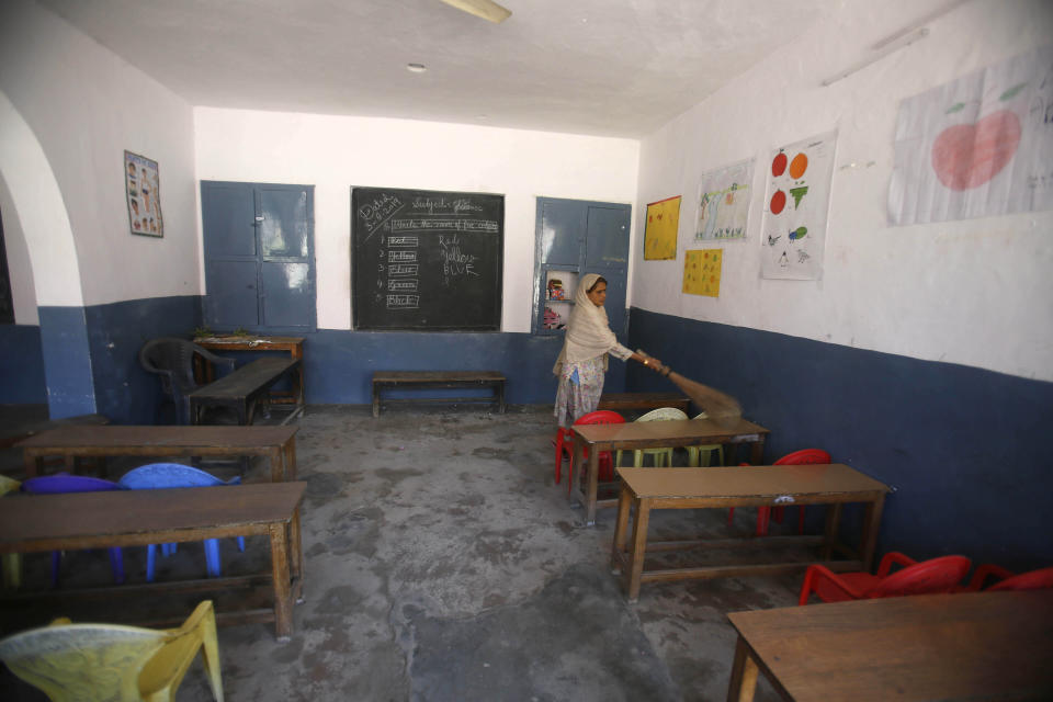 A Kashmiri school staff member cleans a deserted classroom in Srinagar, Indian controlled Kashmir, Monday, Aug. 19, 2019. Restrictions continue in much of Indian-administered Kashmir, despite India's government saying it was gradually restoring phone lines and easing a security lockdown that's been in place for nearly two weeks. (AP Photo/Mukhtar Khan)